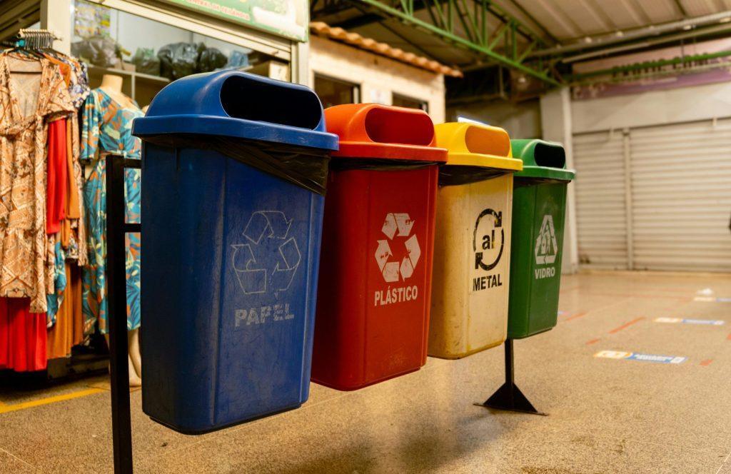 Multiple labeled recycling and waste bins placed together in a clean indoor public area.