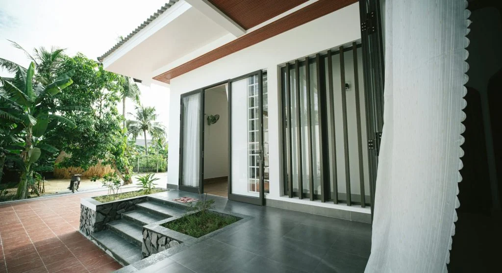 Small front yard trees creating shade on front steps to improve entry comfort during hot weather