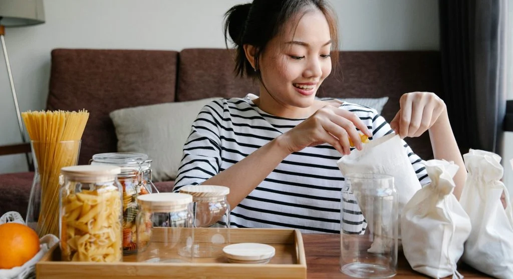 Putting a reusable jar into a clearly marked box for returnable packaging at home